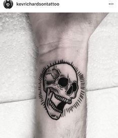 a man's arm with a black and white skull tattoo on the left forearm