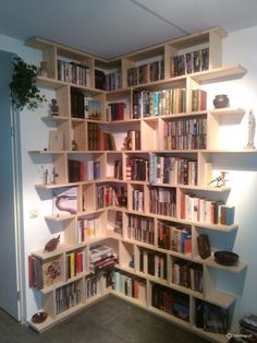 a corner book shelf filled with lots of books next to a wall mounted planter