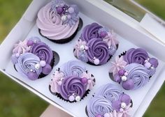 there are six cupcakes with purple frosting in the shape of flowers and pearls