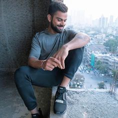 a man sitting on top of a cement wall next to a cityscape with buildings in the background