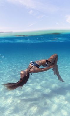 a woman is swimming in the ocean with long hair