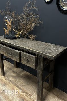 a wooden table with two drawers and a glass vase on it's end shelf