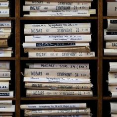 many books are stacked on top of each other in a bookcase with wooden shelves