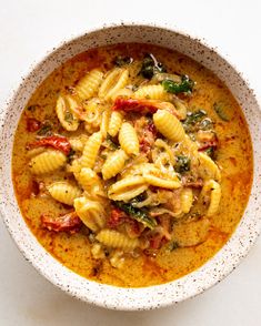 a white bowl filled with pasta and spinach soup