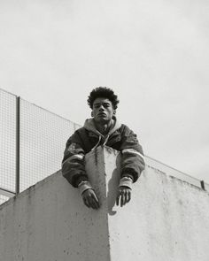 a young man leaning on the side of a wall