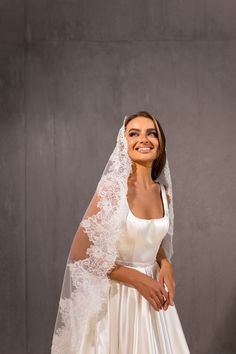 a woman in a white wedding dress and veil posing for the camera with her hands on her hips