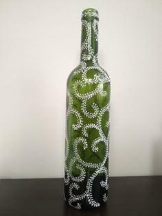 a green bottle sitting on top of a wooden table next to a white and black wall