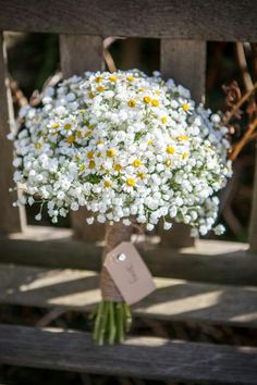 a bouquet of flowers sitting on top of a wooden bench next to a price tag