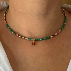 a woman wearing a necklace with beads and a gold charm on it's neck