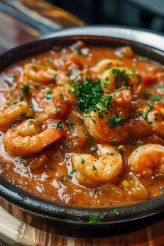 a bowl filled with shrimp and sauce on top of a wooden table