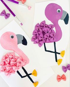 two flamingos made out of paper and some crafting supplies on a white table