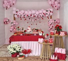 a table topped with lots of pink and red balloons next to tables filled with cakes