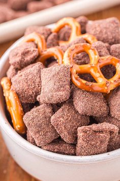 a white bowl filled with chocolate covered pretzels and pretzel shaped pretzels