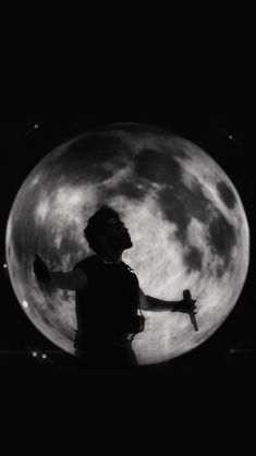 a person standing in front of the moon with their arms out and hands outstretched up