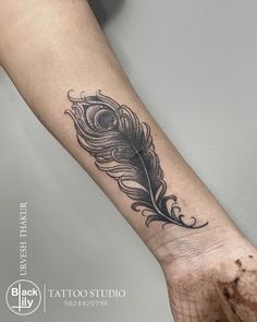 a black and white feather tattoo on the arm