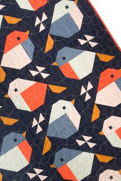 a quilted table runner with colorful birds on black and orange squares in the center