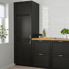 a kitchen with black cabinets and wooden counter tops in front of a white brick wall