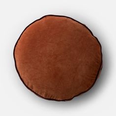 a brown round cushion sitting on top of a white floor