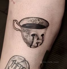 a tattoo on the leg of a person with a cup of coffee