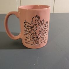 a pink coffee mug with an image of cartoon characters painted on it's side