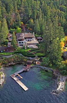 an aerial view of a house and dock in the middle of a lake surrounded by trees