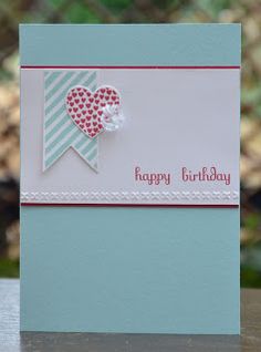 a happy birthday card with a heart and ribbon on the front, sitting on a table