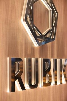 the logo for rubik is displayed in front of a wood paneled wall with metal letters