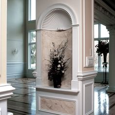 a vase filled with flowers sitting on top of a white pillar next to a window