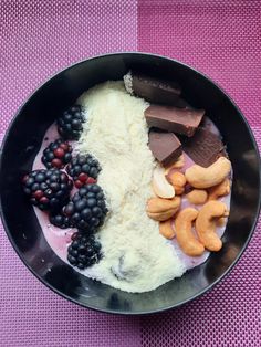 a black bowl filled with different types of food on top of a purple table cloth