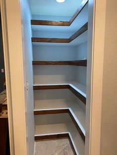 an empty walk in closet with white shelves and wood trim on the bottom half of it