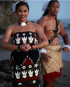 two people in native clothing standing on the beach