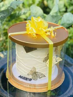 the cake is decorated with yellow flowers and butterflies on it's side, along with a green ribbon