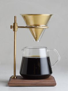 a coffee maker with a wooden base and glass carafe on the top, sitting on a white surface