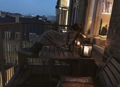 a woman sitting at a table on top of a balcony next to a lit candle