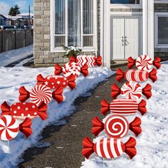 red and white candy canes are lined up in front of a house with snow on the ground