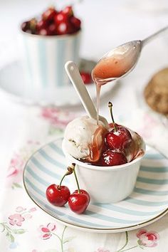 cherries are being drizzled over ice cream in a bowl on a plate