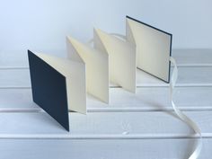 an open book sitting on top of a table next to a white ribbon and two black books