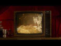 an old fashioned television sitting on top of a wooden table next to glasses and bottles