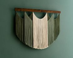 a wall hanging made out of macrame string and wooden dows on a green wall