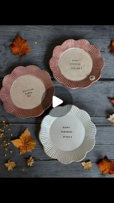 three plates sitting on top of a wooden table next to leaves and acorns