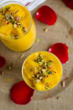 two glasses filled with orange juice and garnished with pistachio on top