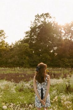 a woman standing in a field with her back to the camera