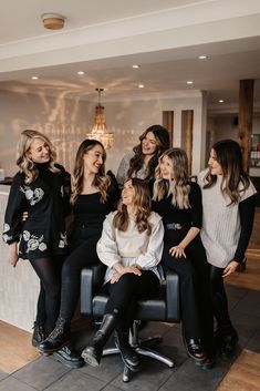 a group of women sitting next to each other on top of a chair in a room