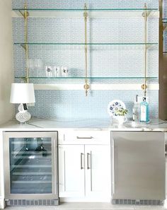 a kitchen with white cabinets and glass shelves