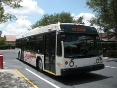 a white bus driving down a street next to a red fire hydrant and trees