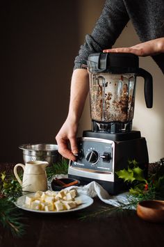 a person using a blender on top of a table next to other food items