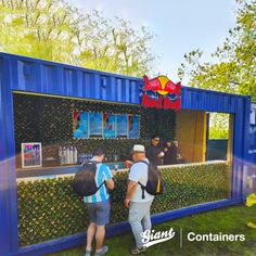 people are standing in front of a blue container that has plants growing out of it