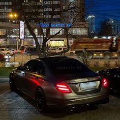 two cars are parked on the side of the road at night in front of some buildings