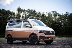 a van parked in front of trees on a gravel road with no one around it