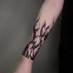 a man's arm with black and white tattoo design on the left side of his arm